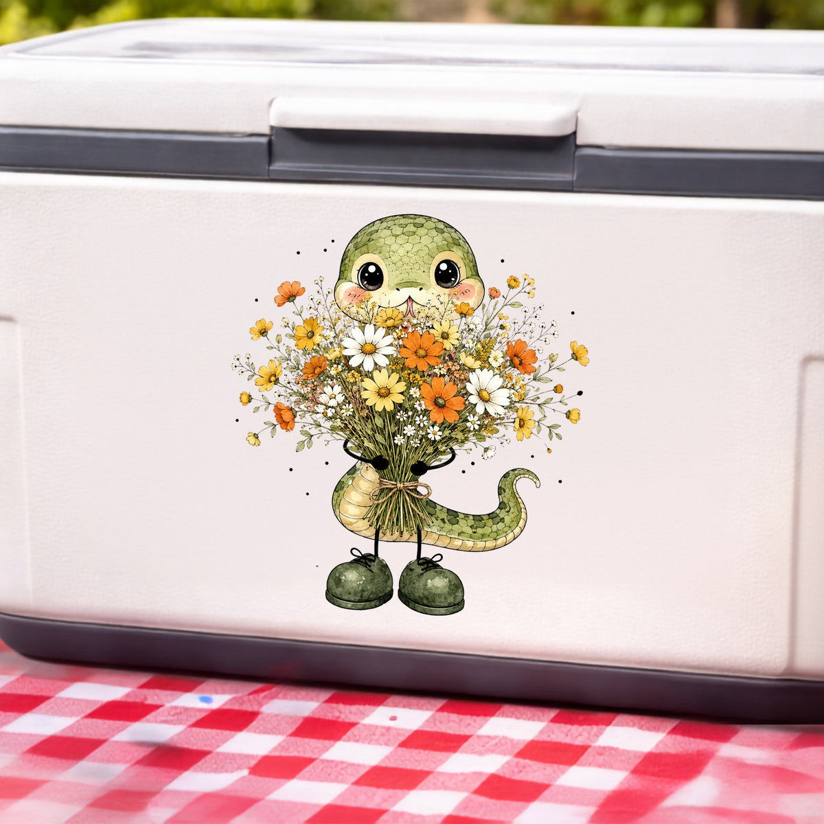 Green Snake Holding Wildflower Bouquet UV DTF sticker applied to a white cooler on a red gingham cloth