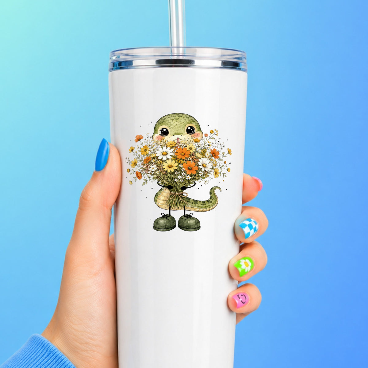 Green Snake Holding Wildflower Bouquet UV DTF sticker applied to a white straw tumbler on a blue background