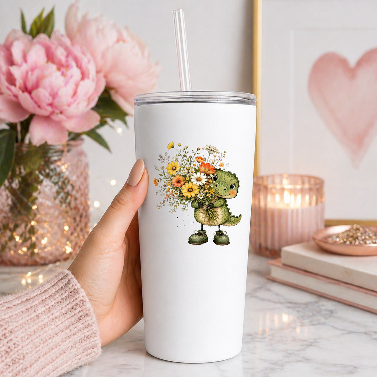 Baby Crocodile Holding Flower Bouquet UV DTF sticker applied to a white straw tumbler beside pink peonies