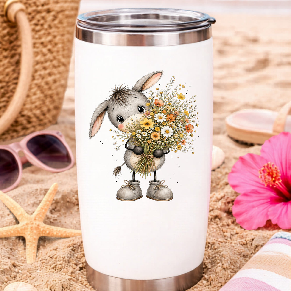 Baby Donkey Holding Wildflower Bouquet UV DTF sticker applied to a white travel tumbler on beach sand