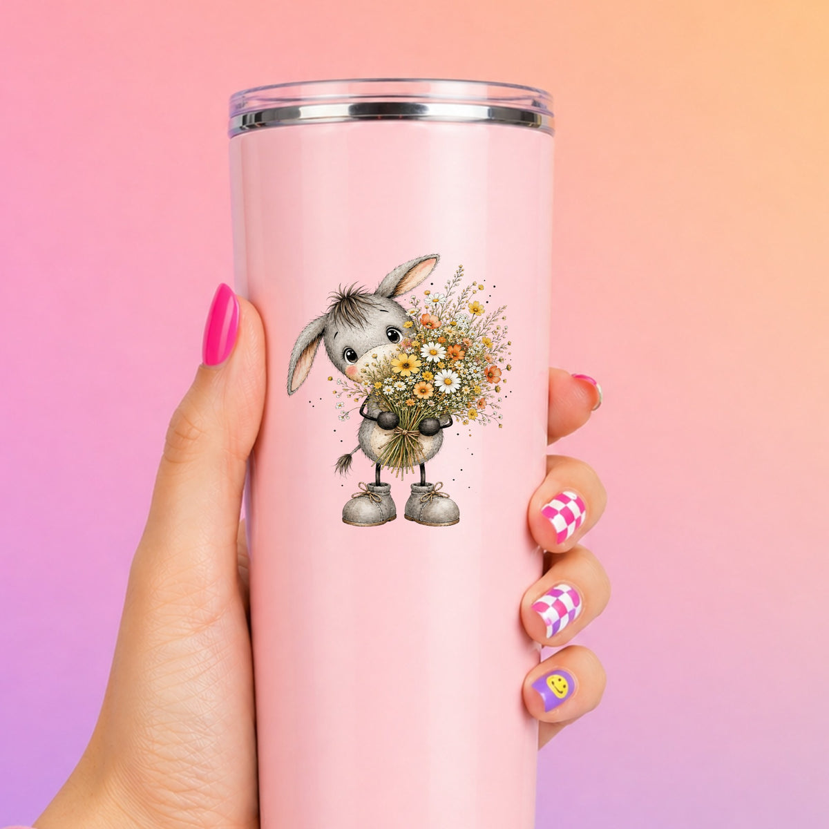 Baby Donkey Holding Wildflower Bouquet UV DTF sticker applied to a tall pink tumbler on a pink and orange background
