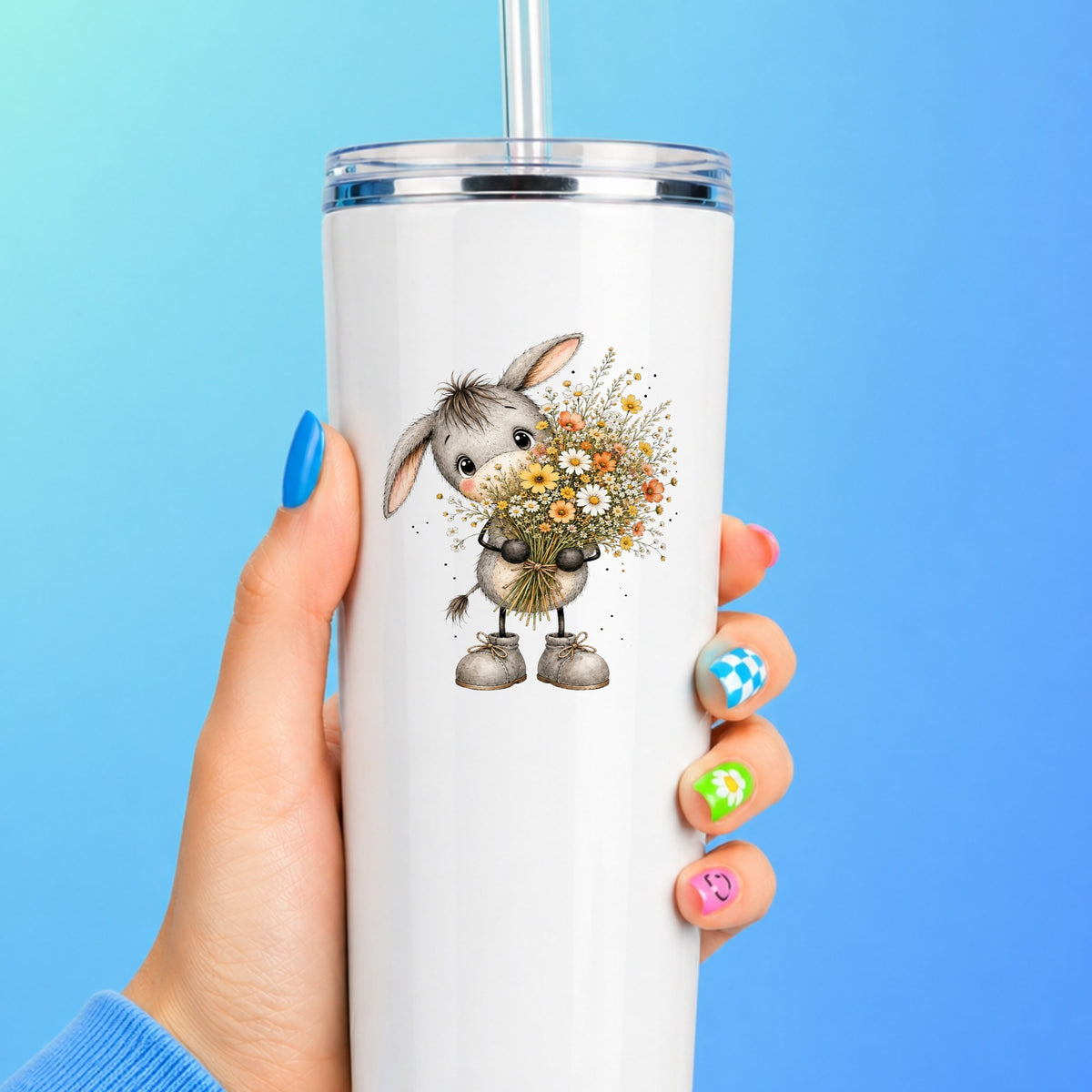 Baby Donkey Holding Wildflower Bouquet UV DTF sticker applied to a white straw tumbler on a blue background