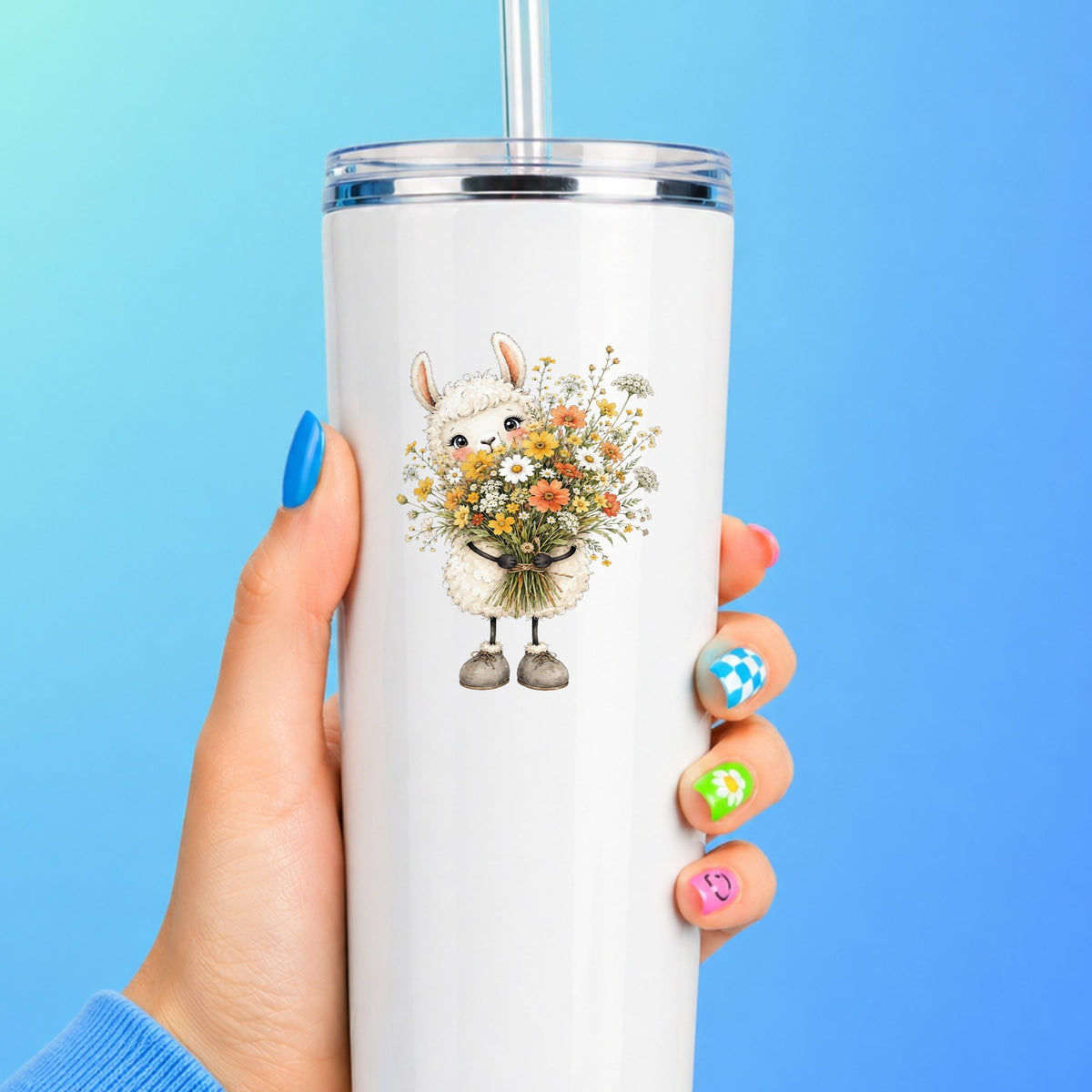 White Llama Holding Daisy Bouquet UV DTF sticker applied to a white straw tumbler on a blue background