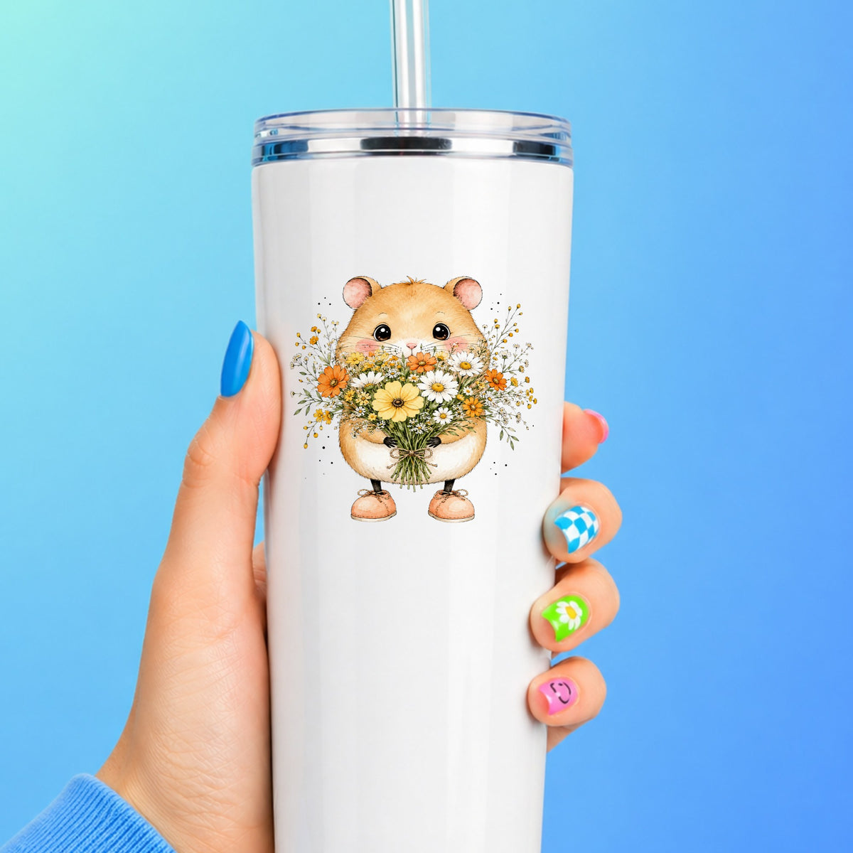 Hamster Holding Wildflower Bouquet UV DTF sticker applied to a white straw tumbler on a blue background