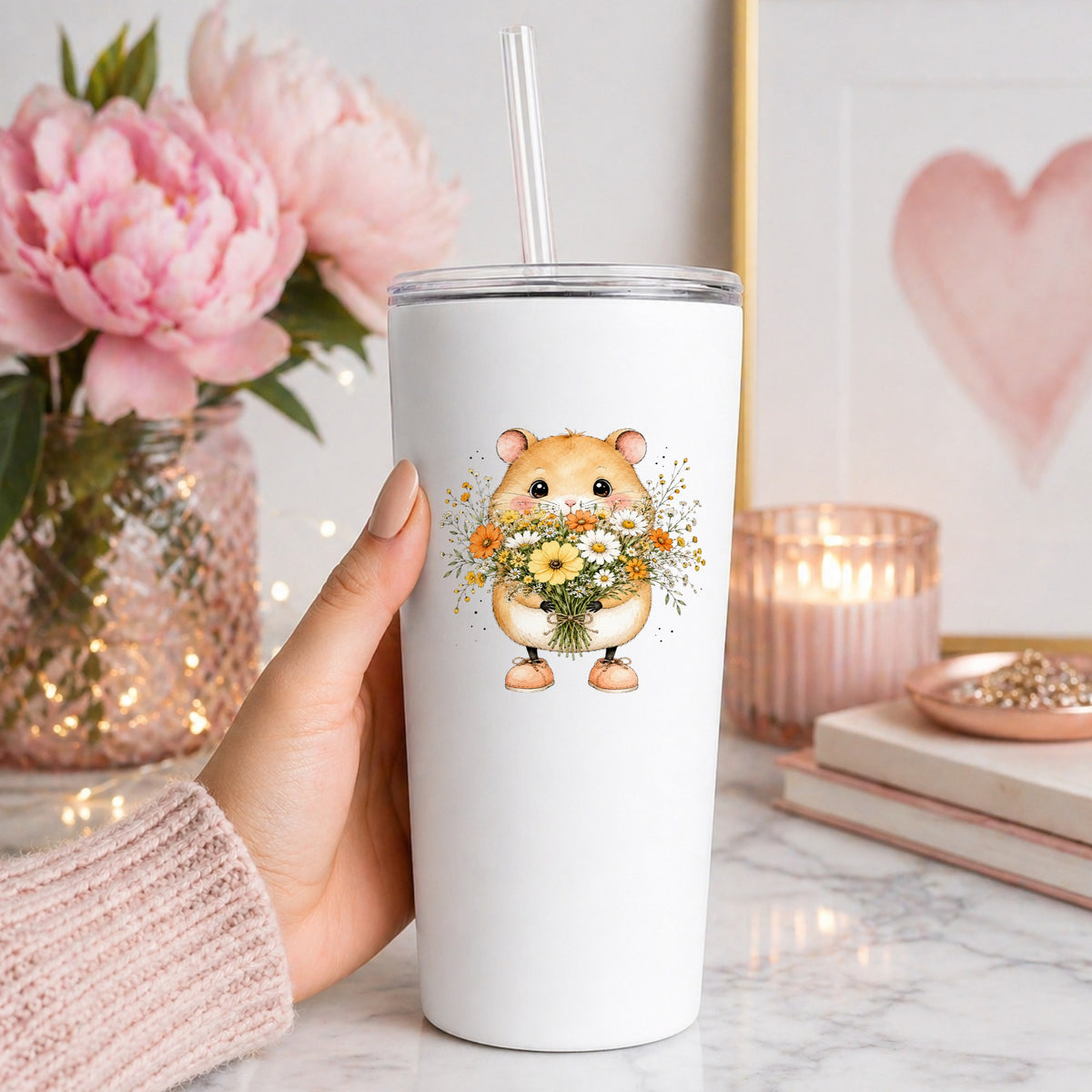 Hamster Holding Wildflower Bouquet UV DTF sticker applied to a white straw tumbler beside pink peonies