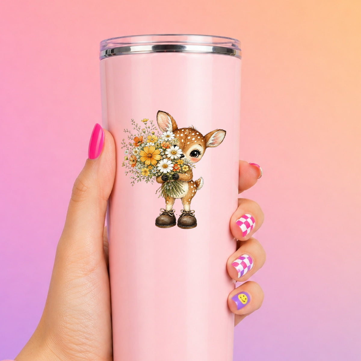 Baby Deer Holding Wildflower Bouquet UV DTF sticker applied to a tall pink tumbler on a pink and orange background