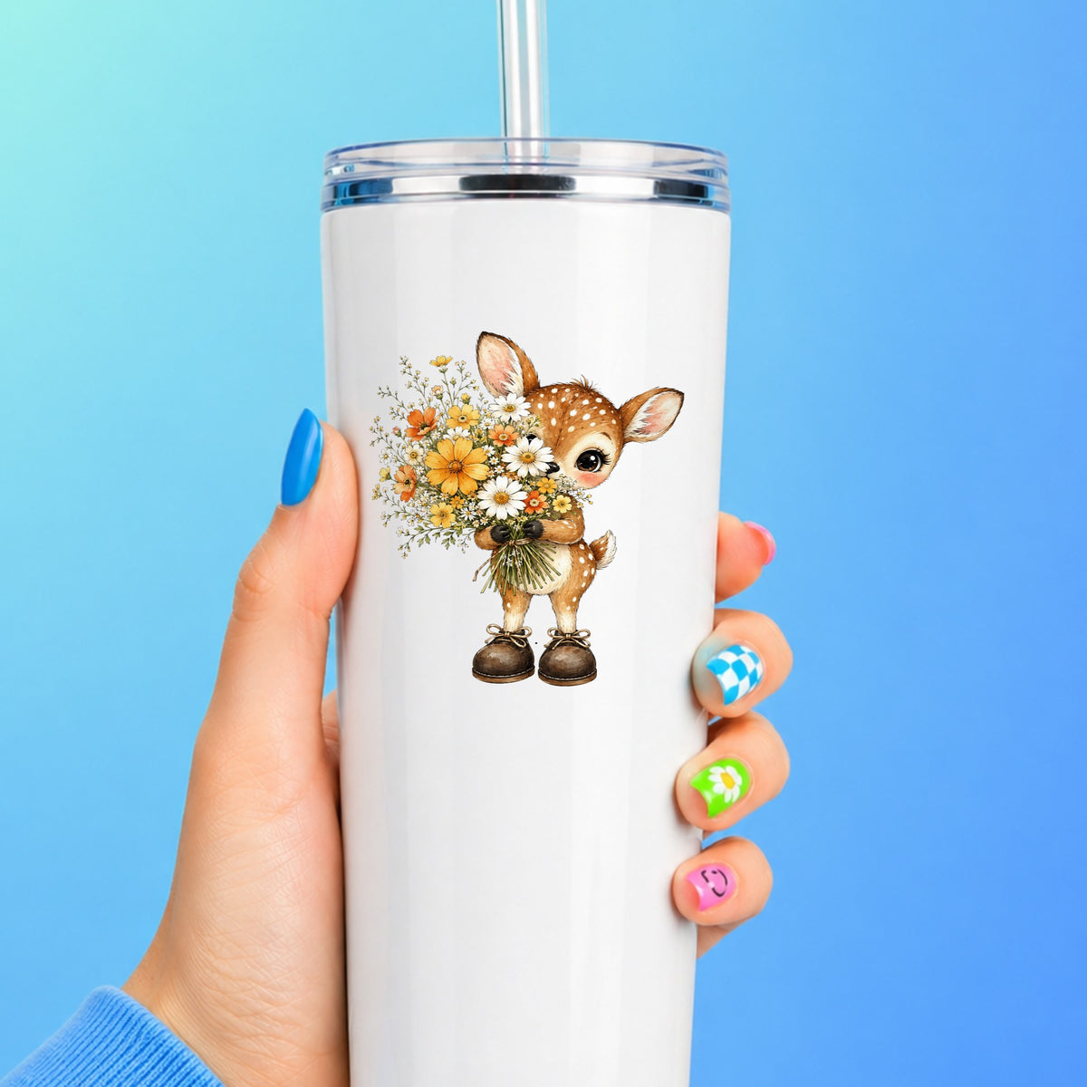 Baby Deer Holding Wildflower Bouquet UV DTF sticker applied to a white straw tumbler on a blue background