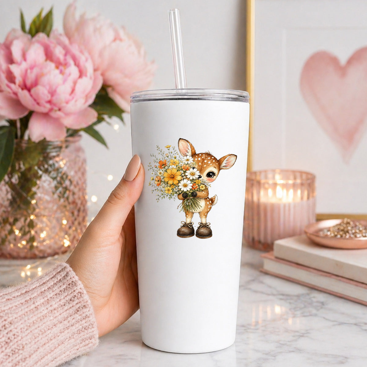 Baby Deer Holding Wildflower Bouquet UV DTF sticker applied to a white straw tumbler beside pink peonies