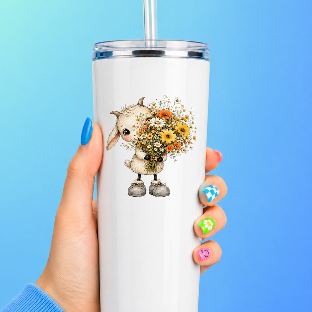 Baby Goat Holding Wildflower Bouquet UV DTF sticker applied to a white straw tumbler on a blue background