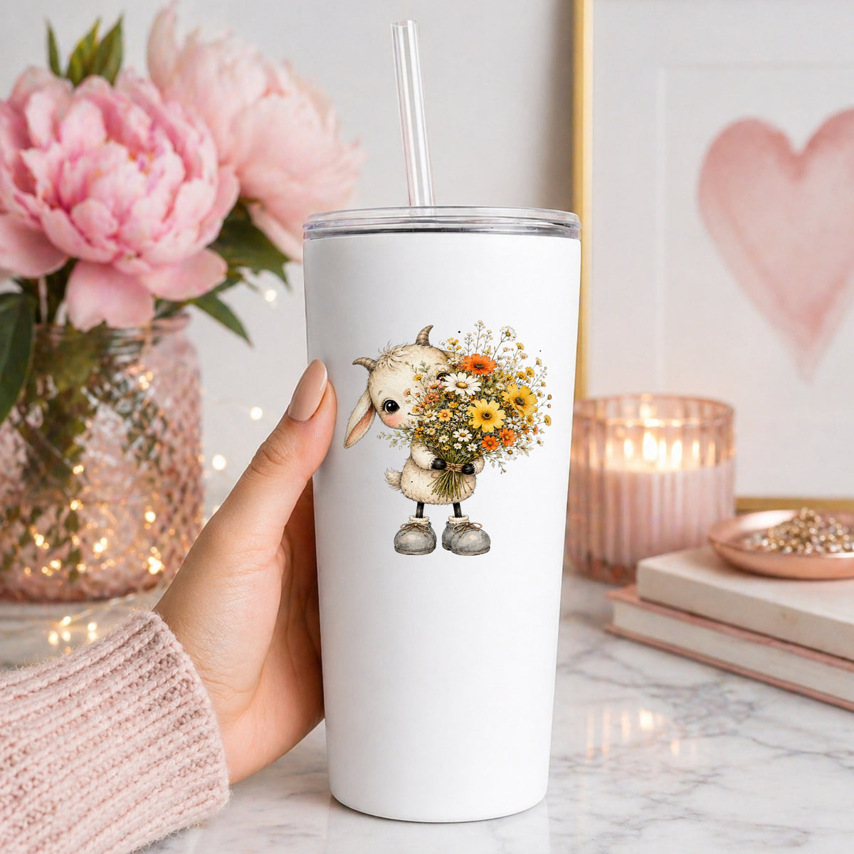 Baby Goat Holding Wildflower Bouquet UV DTF sticker applied to a white straw tumbler beside pink peonies