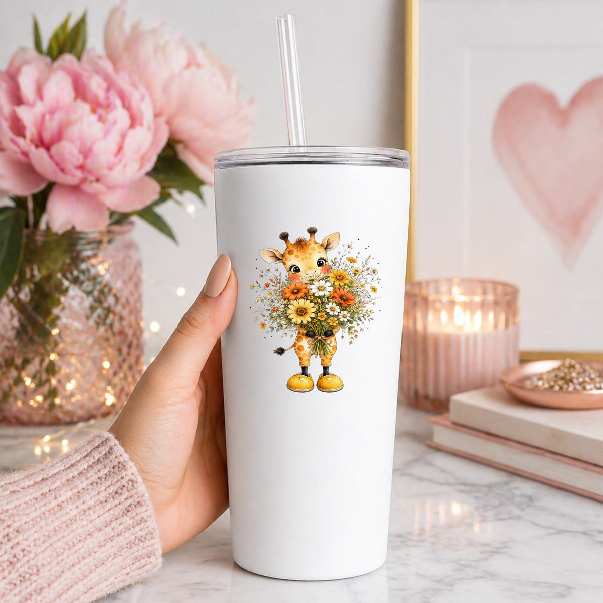 Watercolor Giraffe Holding Daisy Bouquet UV DTF sticker applied to a white straw tumbler beside pink peonies