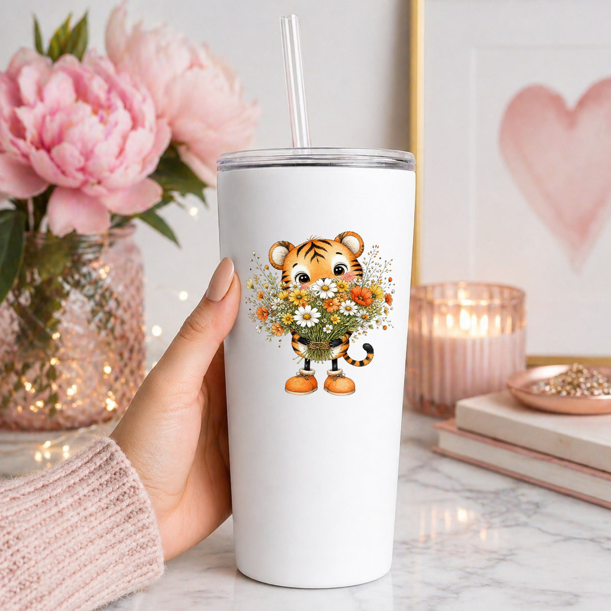 Tiger Cub Holding Wildflower Bouquet UV DTF sticker applied to a white straw tumbler beside pink peonies