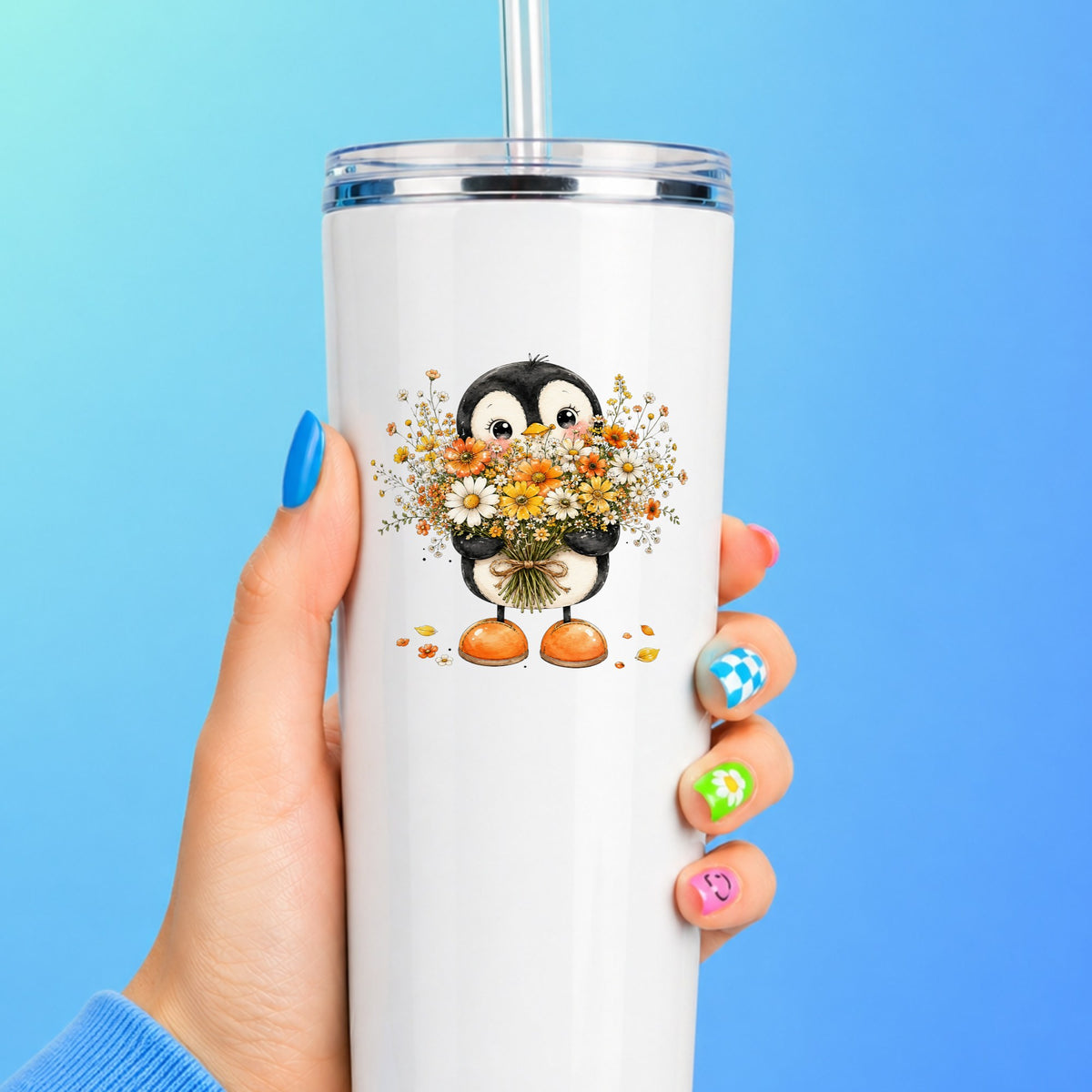 Baby Penguin Holding Wildflower Bouquet UV DTF sticker applied to a white straw tumbler on a blue background