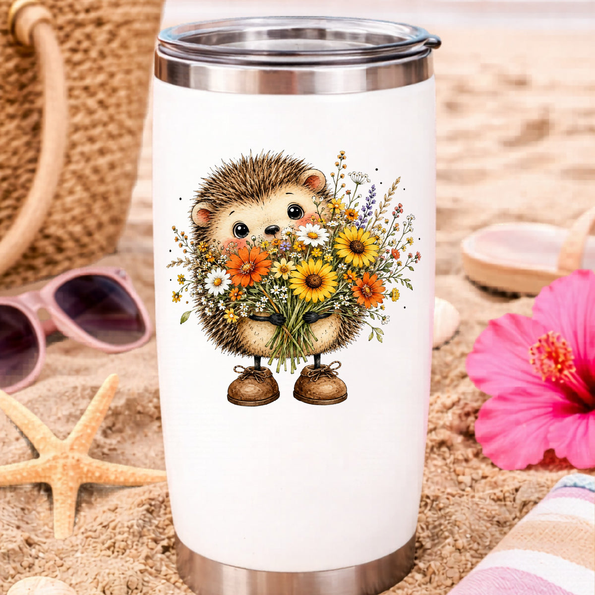 Hedgehog Holding Wildflower Bouquet UV DTF sticker applied to a white travel tumbler on beach sand