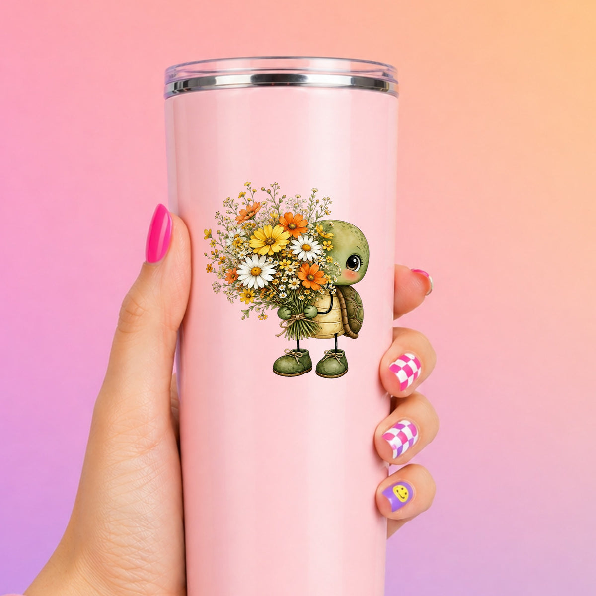 Baby Turtle Holding Wildflower Bouquet UV DTF sticker applied to a tall pink tumbler on a pink and orange background