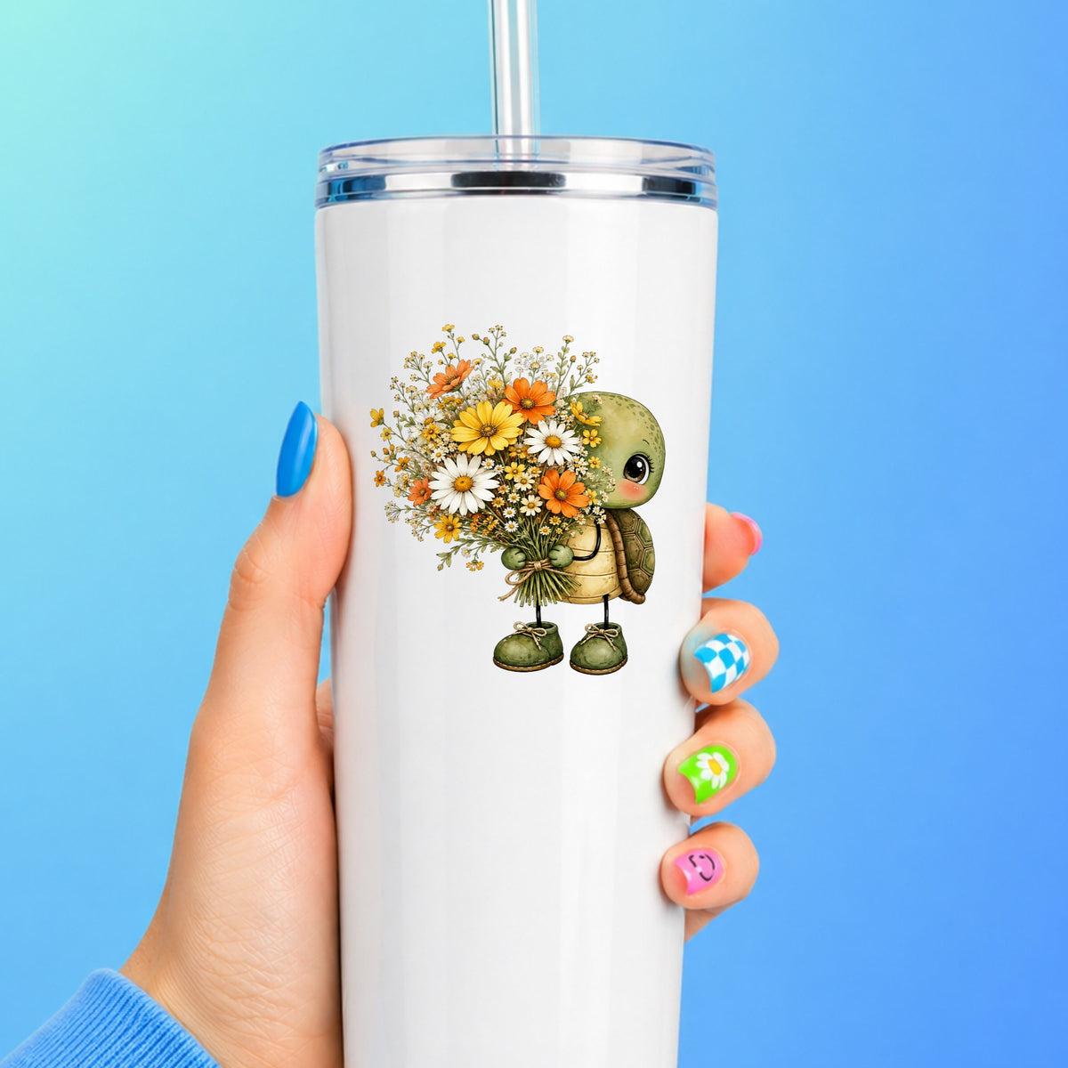 Baby Turtle Holding Wildflower Bouquet UV DTF sticker applied to a white straw tumbler on a blue background