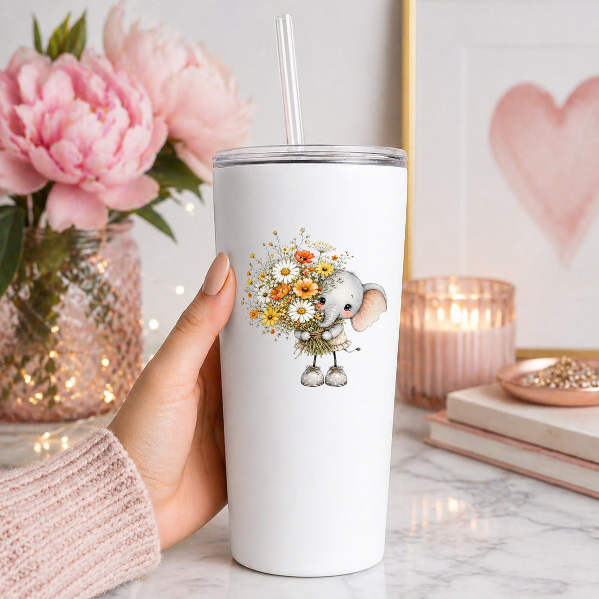 Baby Elephant Holding Daisy Bouquet UV DTF sticker applied to a white straw tumbler beside pink peonies