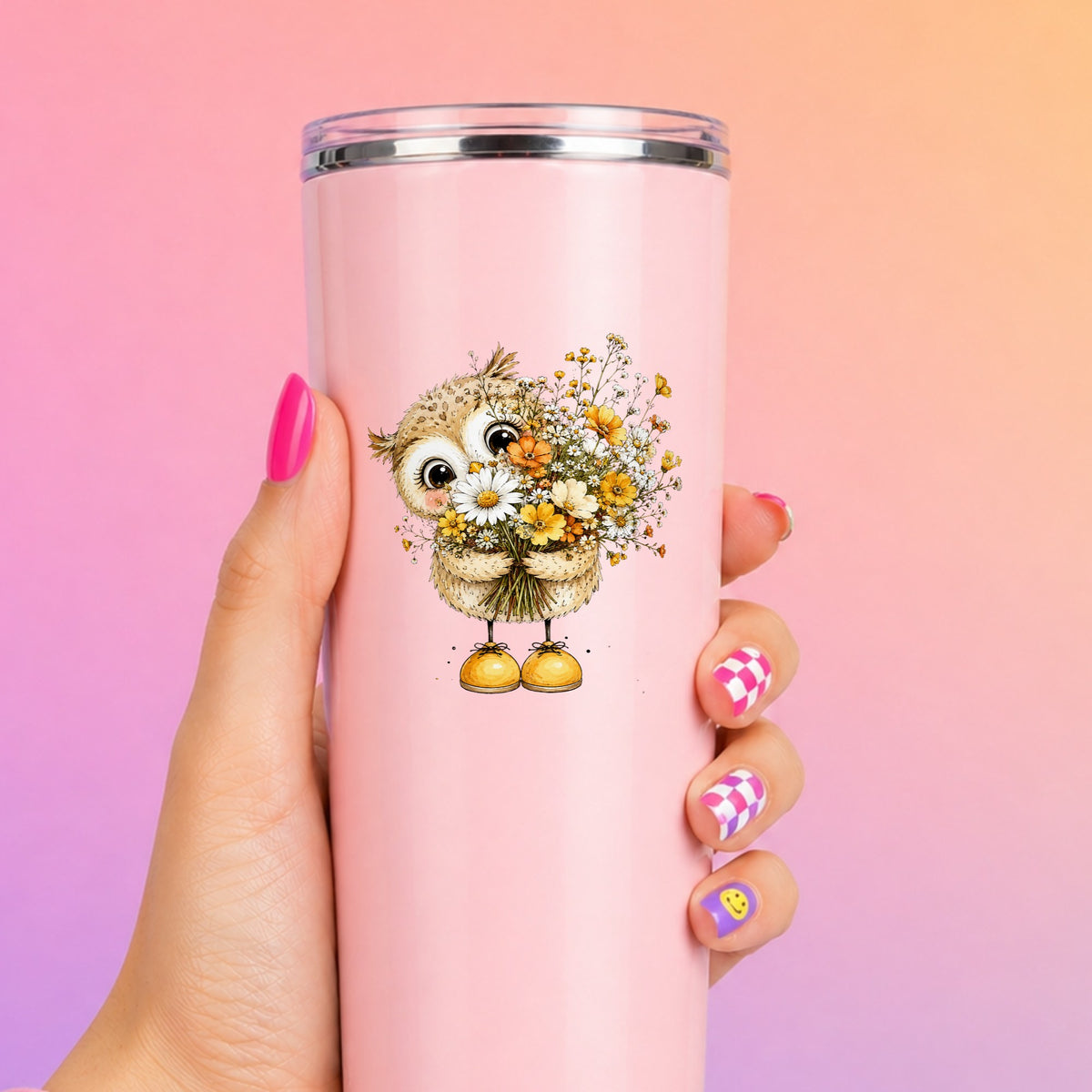 Baby Owl Holding Wildflower Bouquet UV DTF sticker applied to a tall pink tumbler on a pink and orange background