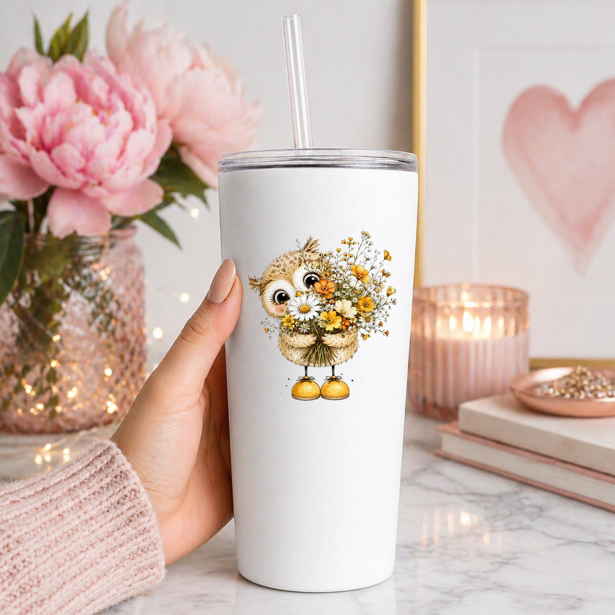Baby Owl Holding Wildflower Bouquet UV DTF sticker applied to a white straw tumbler beside pink peonies