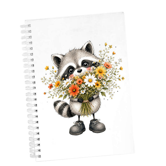 Raccoon Holding Wildflower Bouquet UV DTF sticker applied to the cover of a white spiral journal