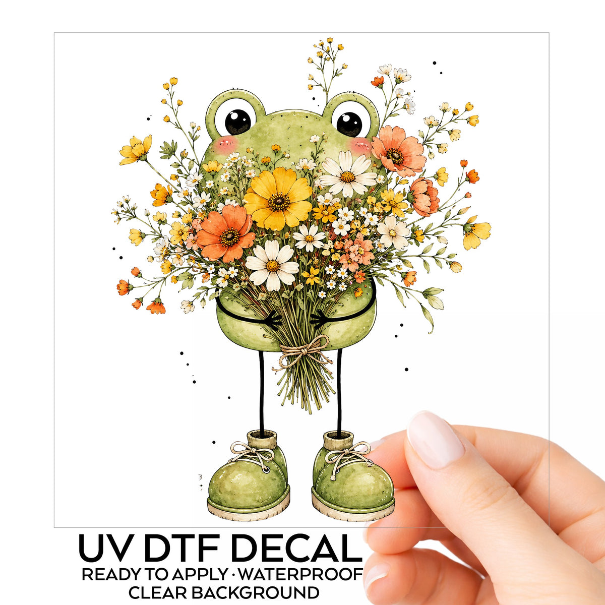 Green Frog Holding Wildflower Bouquet UV DTF sticker on its backing card, held in hand