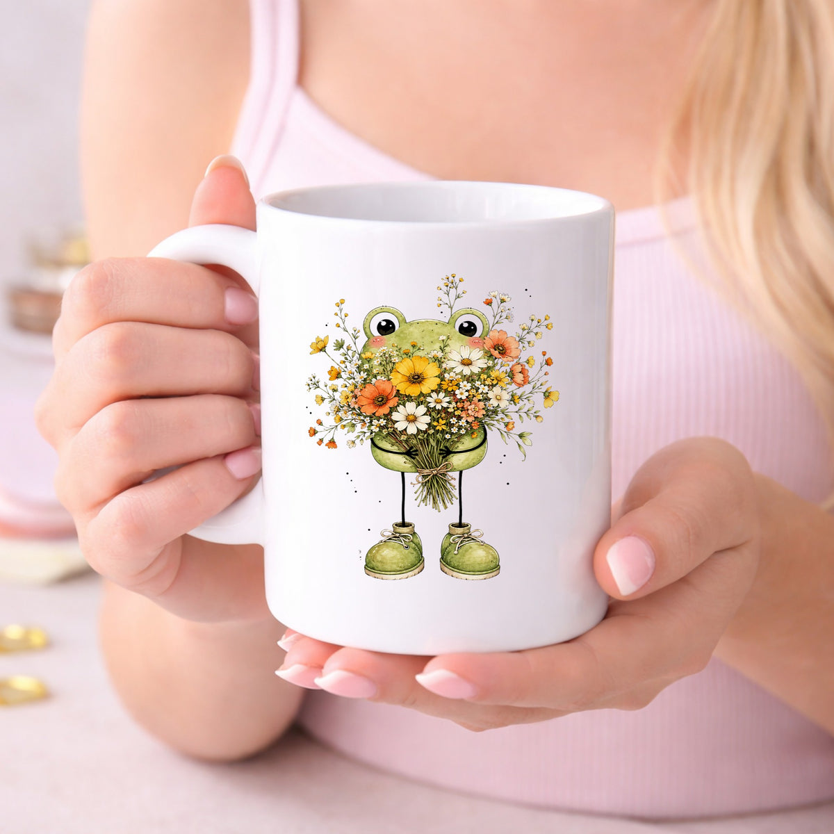 Green Frog Holding Wildflower Bouquet UV DTF sticker applied to a white coffee mug held in both hands
