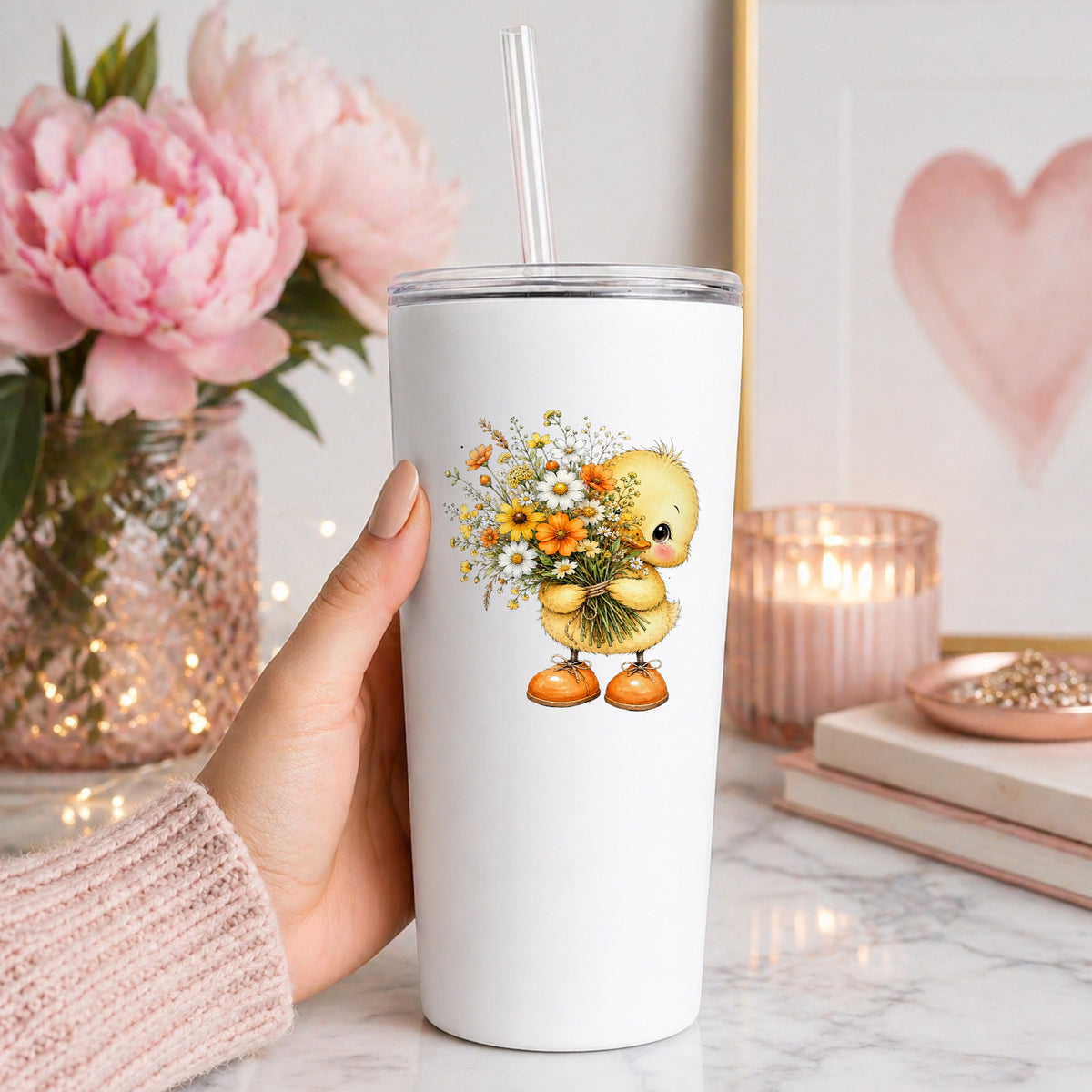 Yellow Duckling Holding Daisy Bouquet UV DTF sticker applied to a white straw tumbler beside pink peonies