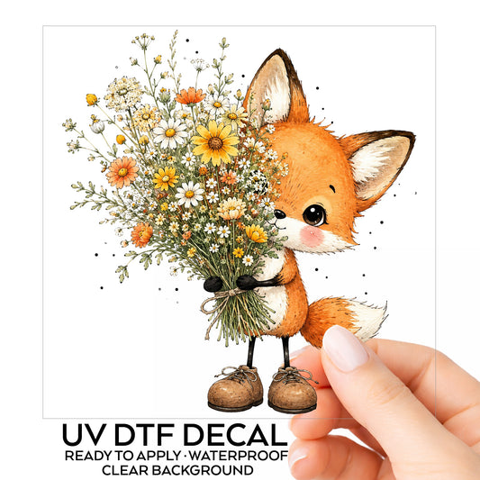 Baby Fox Holding Wildflower Bouquet UV DTF sticker on its backing card, held in hand