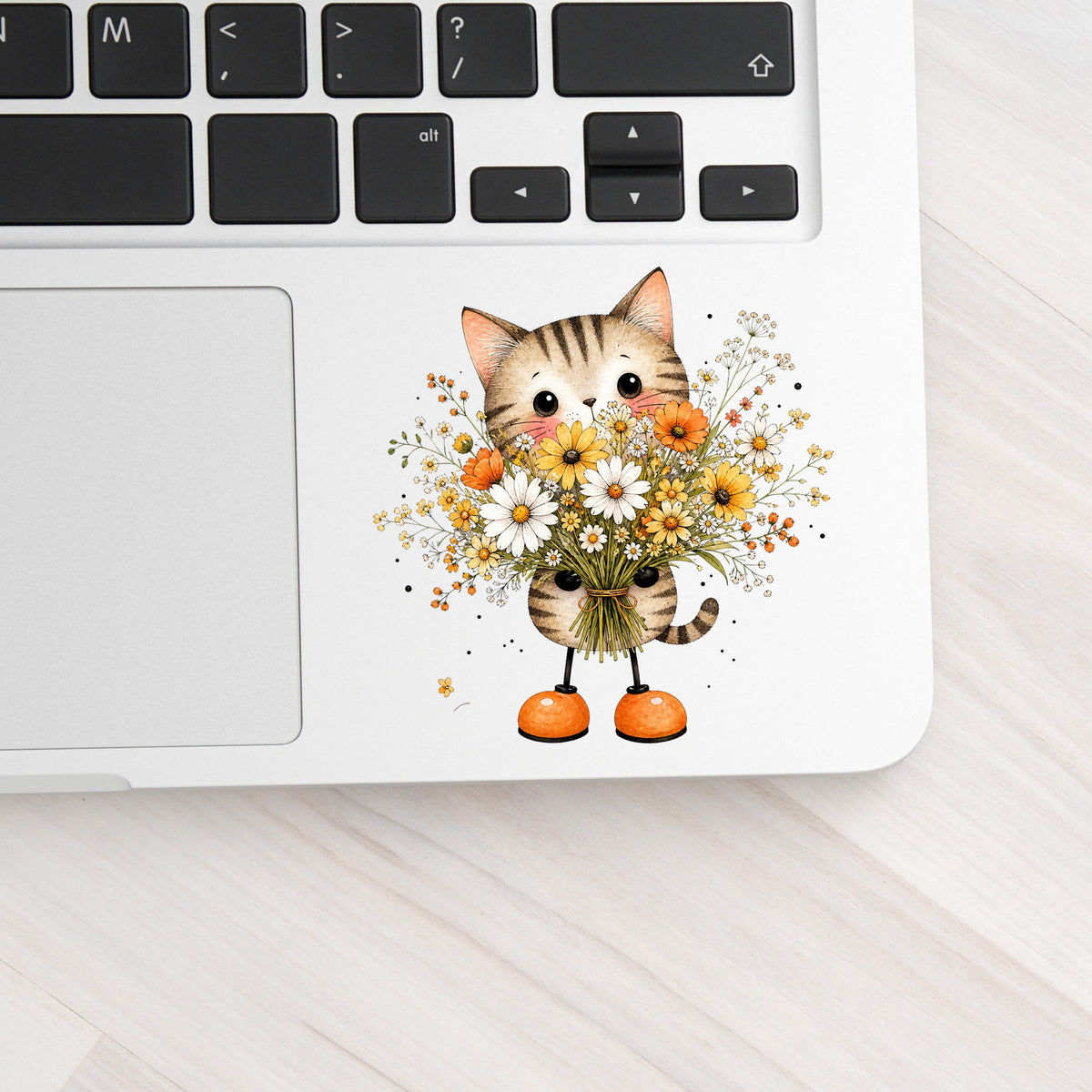 Tabby Cat Holding Daisy Bouquet UV DTF sticker applied to a silver laptop beside the keyboard