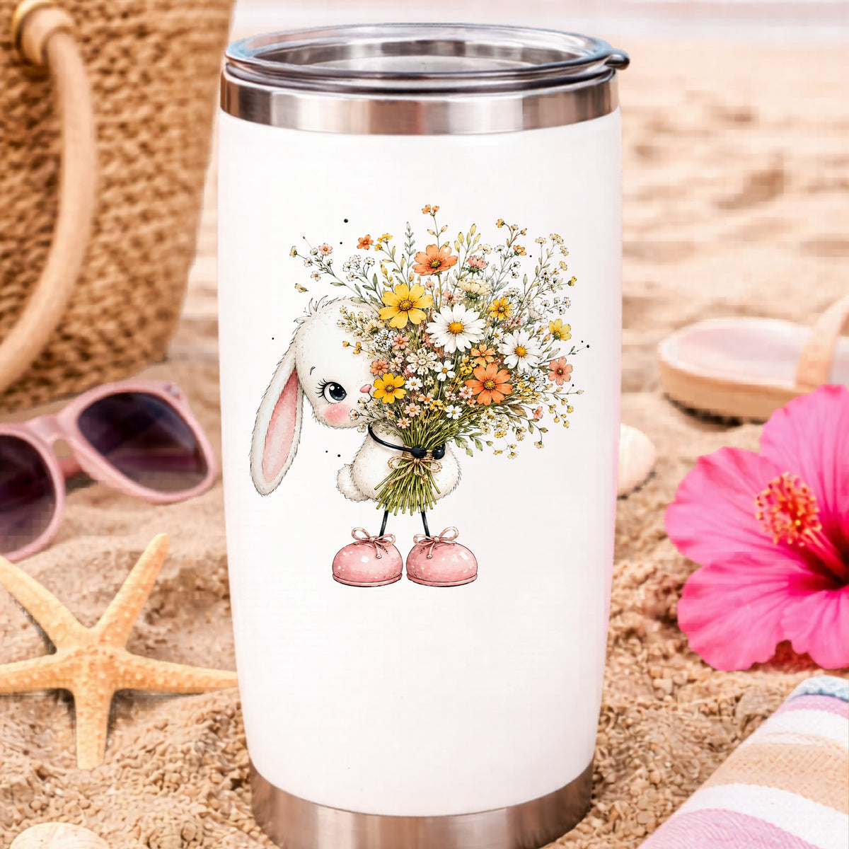White Bunny Holding Wildflower Bouquet UV DTF sticker applied to a white travel tumbler on beach sand