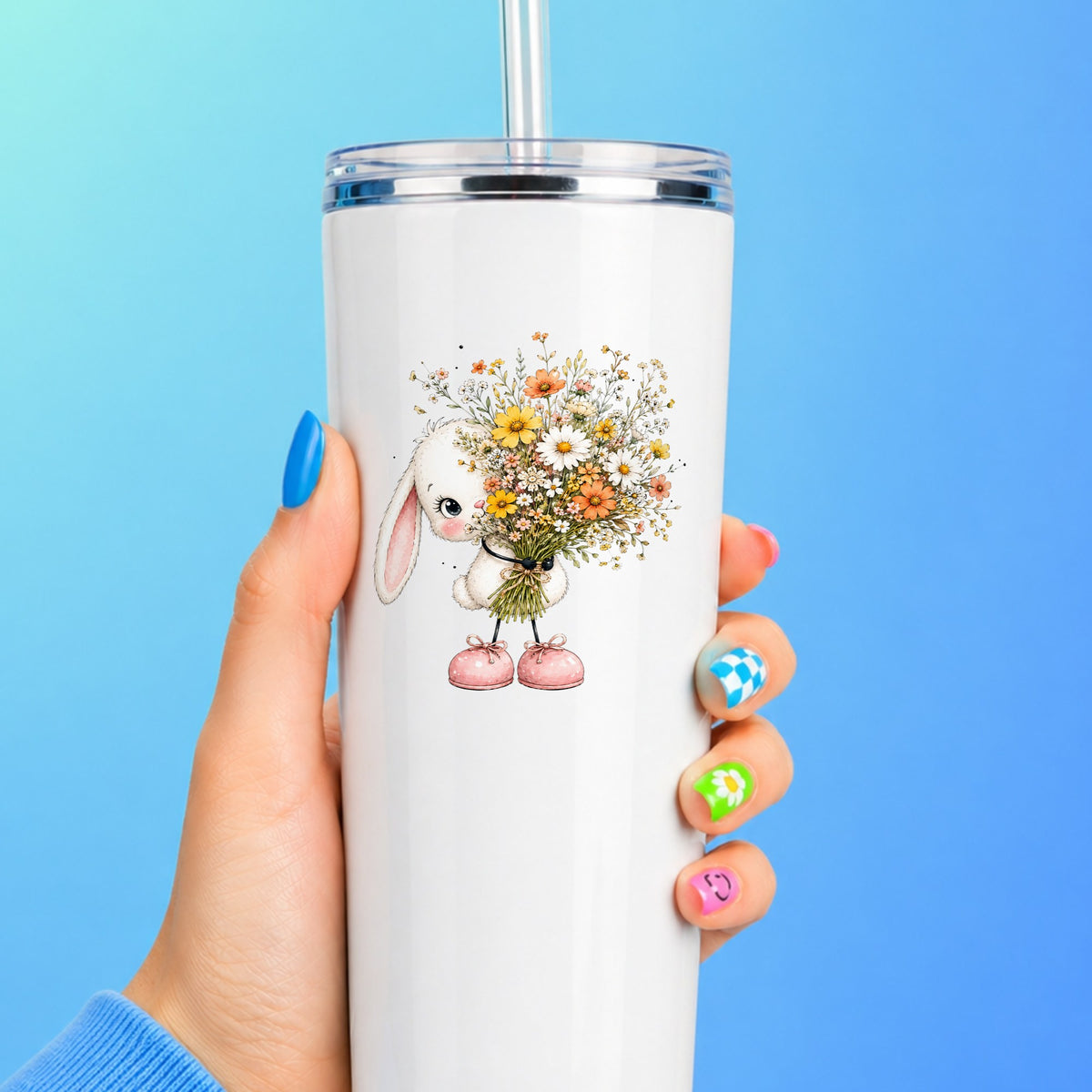 White Bunny Holding Wildflower Bouquet UV DTF sticker applied to a white straw tumbler on a blue background
