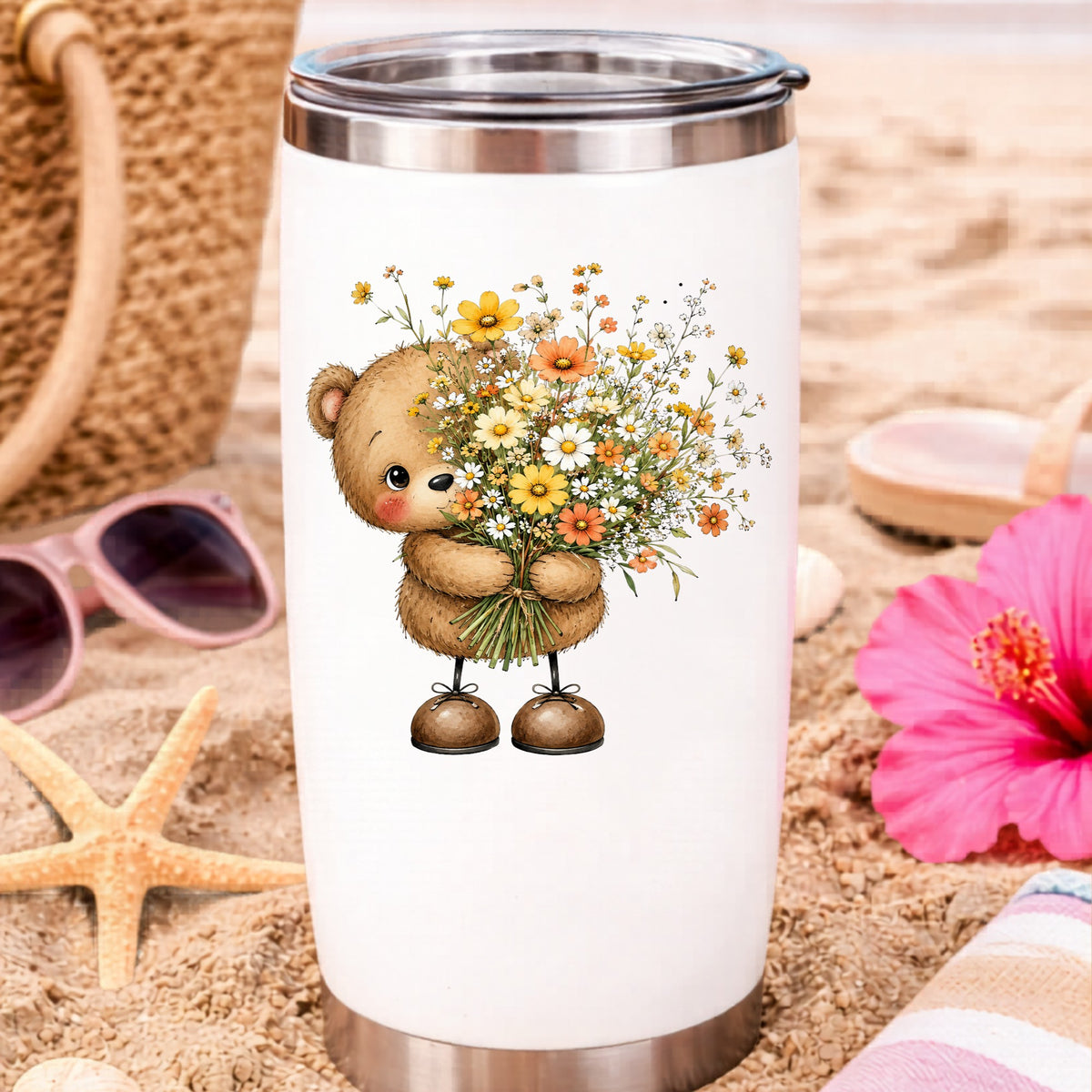 Teddy Bear Holding Wildflower Bouquet UV DTF sticker applied to a white travel tumbler on beach sand