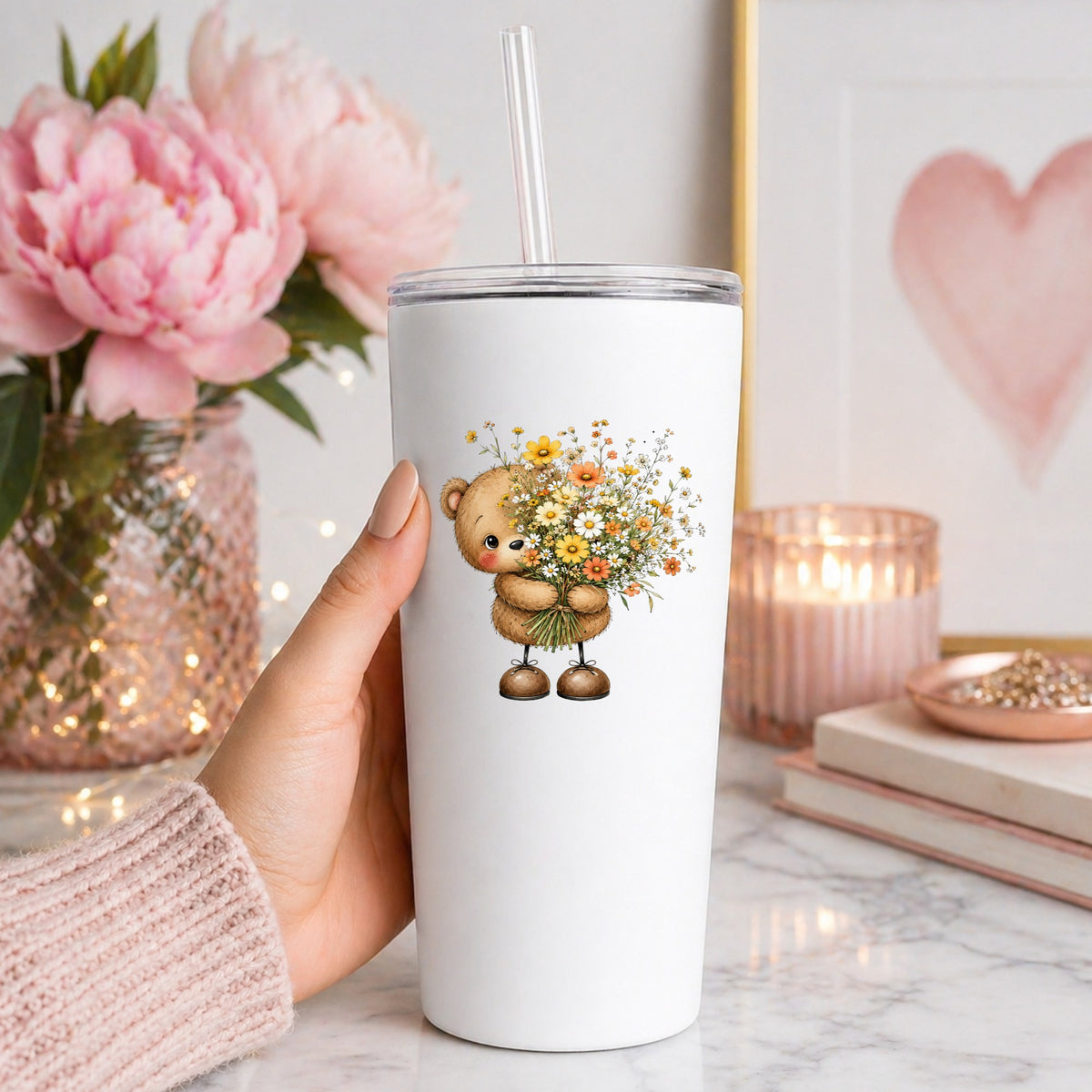 Teddy Bear Holding Wildflower Bouquet UV DTF sticker applied to a white straw tumbler beside pink peonies