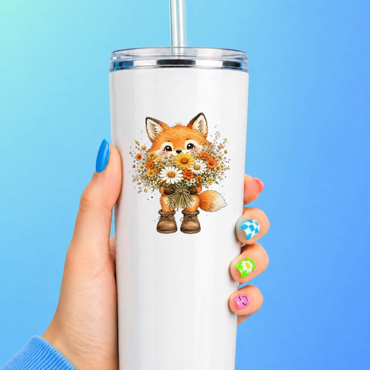 Watercolor Fox Holding Daisy Bouquet UV DTF sticker applied to a white straw tumbler on a blue background