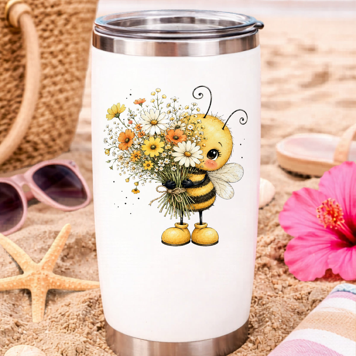 Honey Bee Holding Wildflower Bouquet UV DTF sticker applied to a white travel tumbler on beach sand