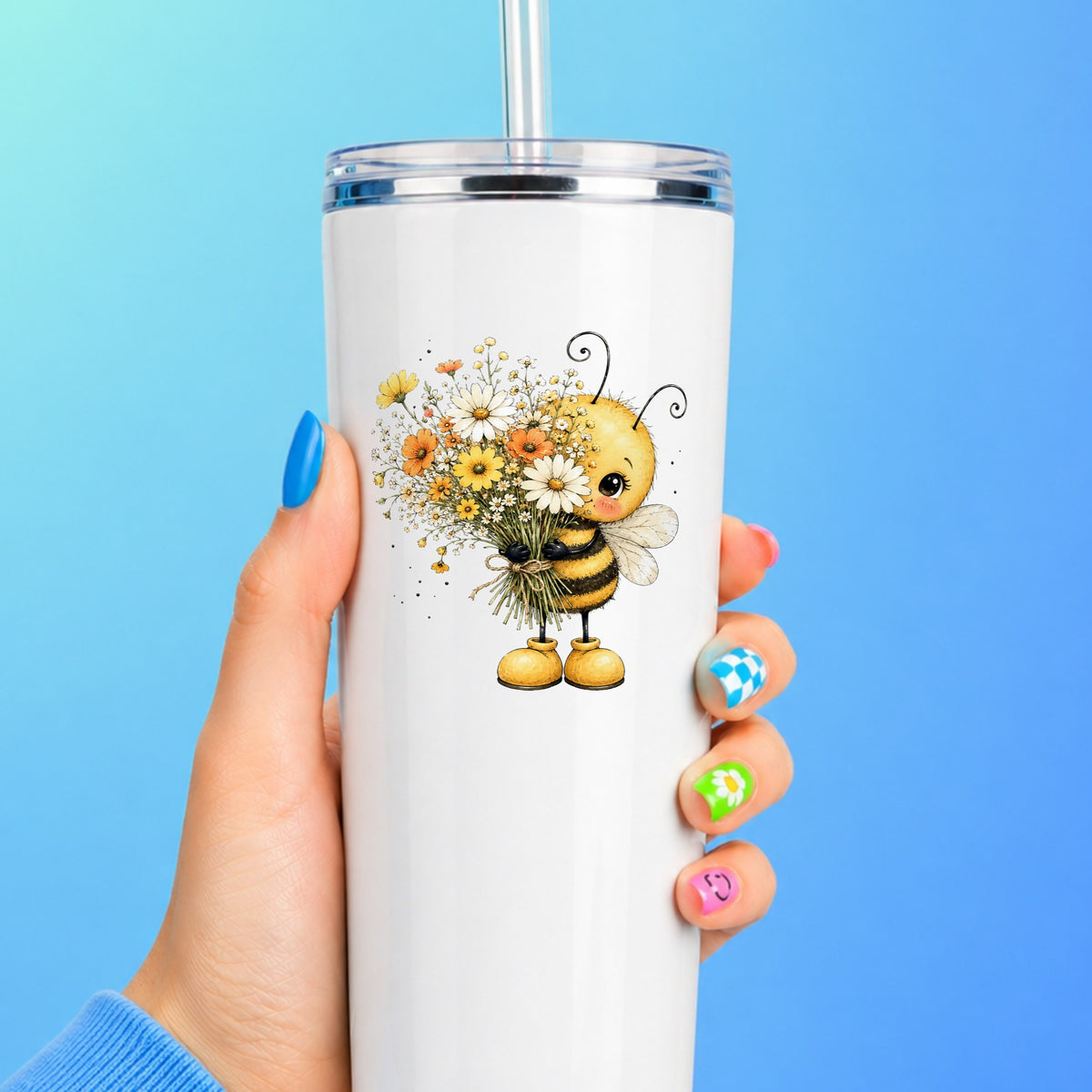 Honey Bee Holding Wildflower Bouquet UV DTF sticker applied to a white straw tumbler on a blue background