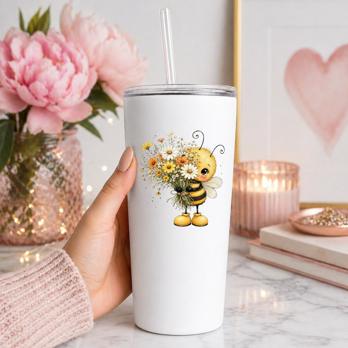 Honey Bee Holding Wildflower Bouquet UV DTF sticker applied to a white straw tumbler beside pink peonies
