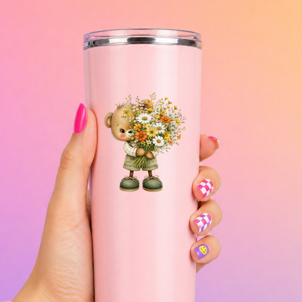 Brown Bear In Overalls Holding Daisy Bouquet UV DTF sticker applied to a tall pink tumbler on a pink and orange background
