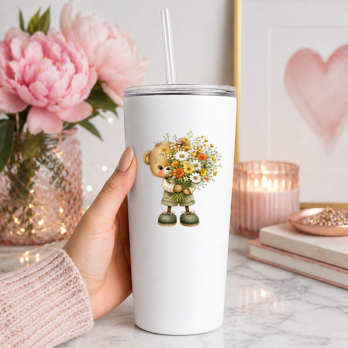 Brown Bear In Overalls Holding Daisy Bouquet UV DTF sticker applied to a white straw tumbler beside pink peonies