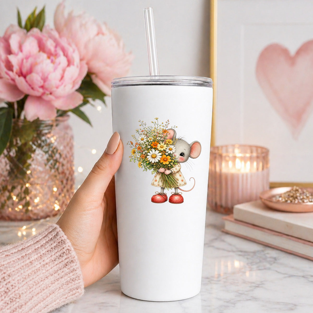 Mouse In Floral Dress Holding Flowers UV DTF sticker applied to a white straw tumbler beside pink peonies