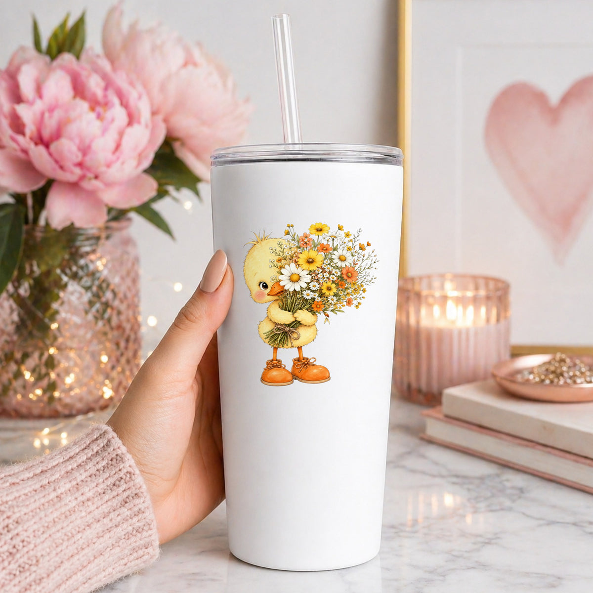 Baby Duck Holding Wildflower Bouquet UV DTF sticker applied to a white straw tumbler beside pink peonies