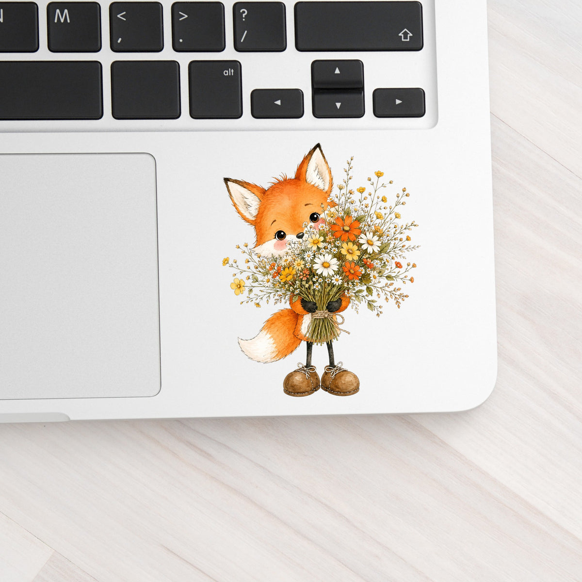 Orange Fox Holding Flower Bouquet UV DTF sticker applied to a silver laptop beside the keyboard