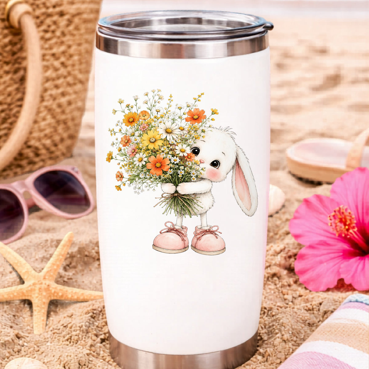 Baby Bunny Holding Daisy Bouquet UV DTF sticker applied to a white travel tumbler on beach sand