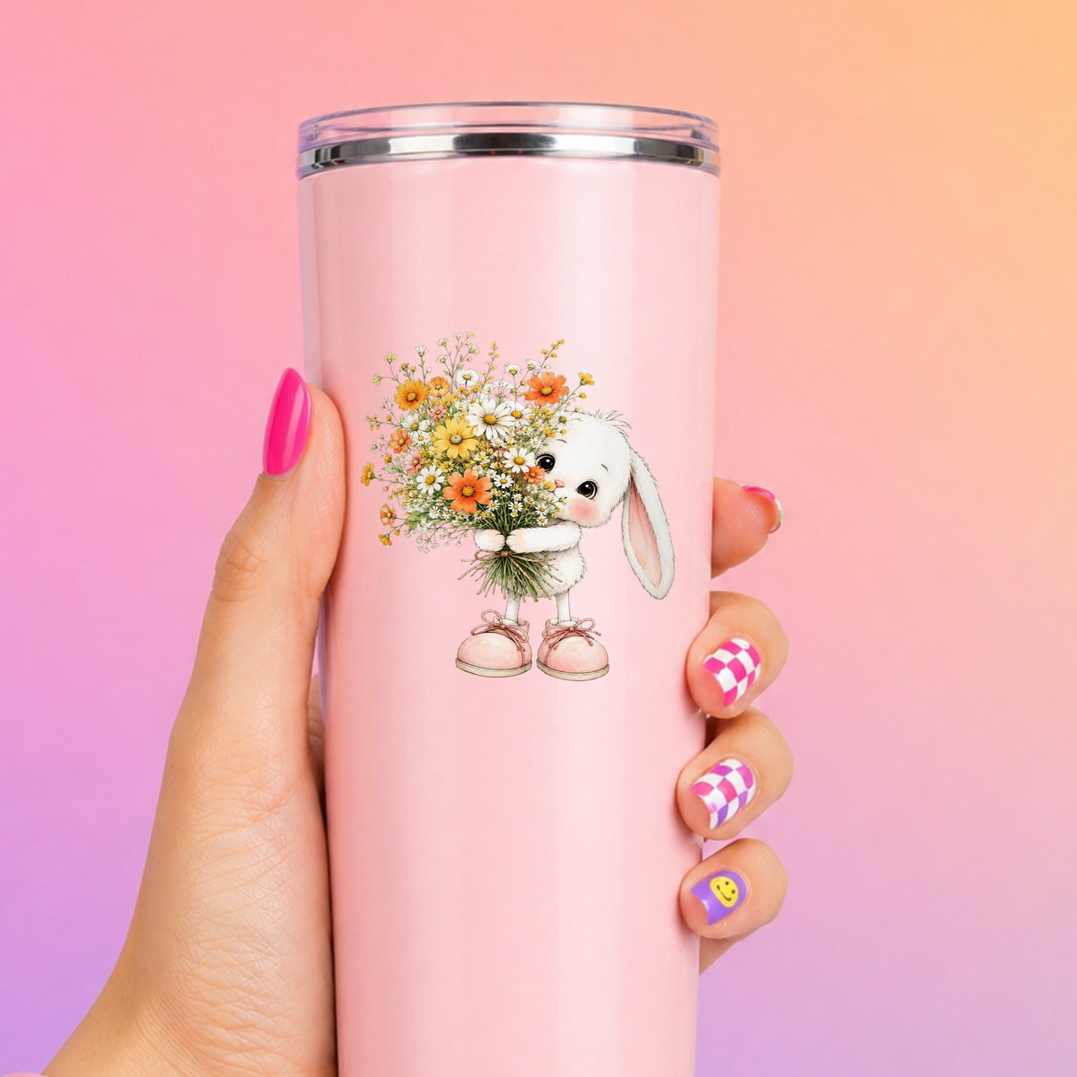 Baby Bunny Holding Daisy Bouquet UV DTF sticker applied to a tall pink tumbler on a pink and orange background