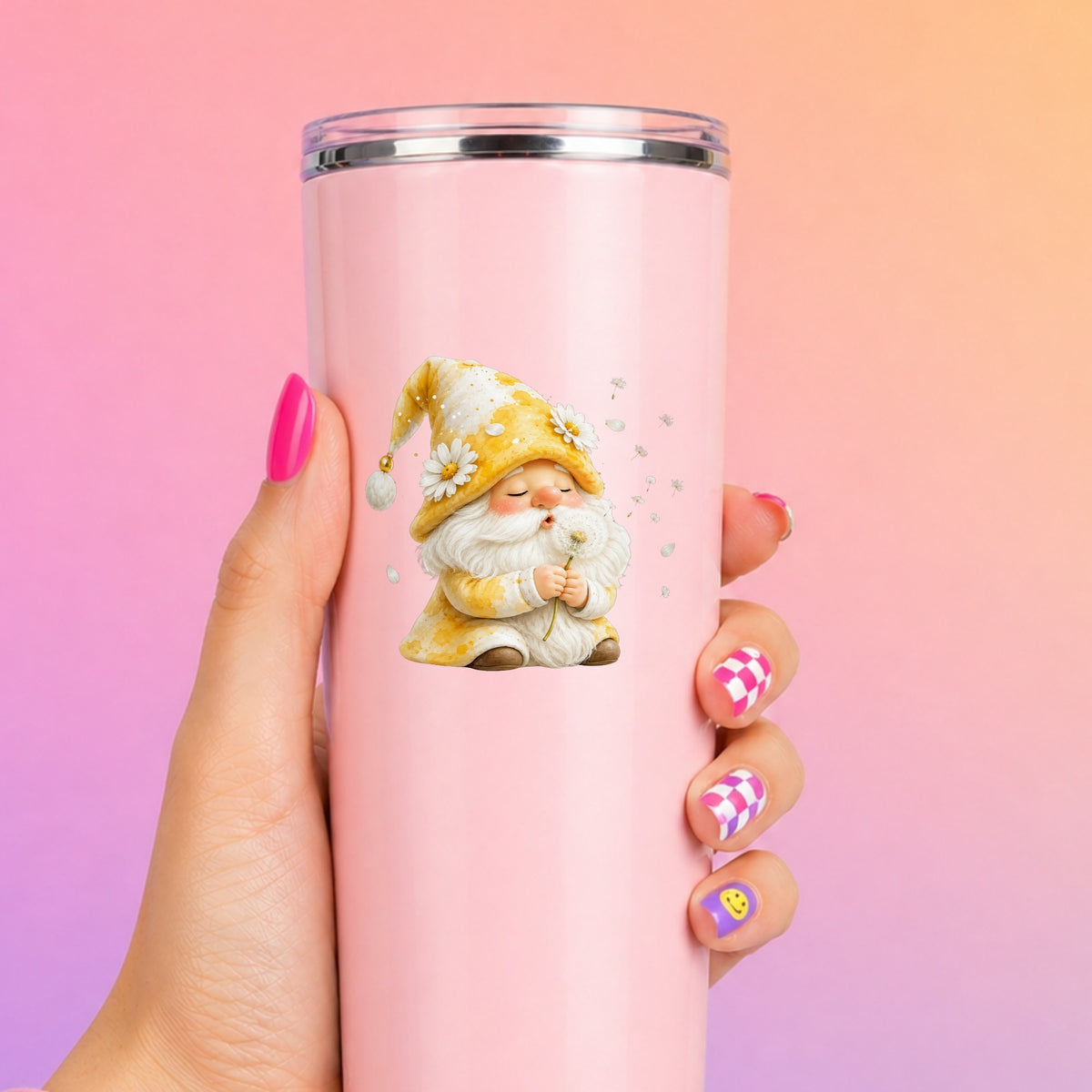 Gnome Blowing A Dandelion UV DTF sticker applied to a tall pink tumbler on a pink and orange background