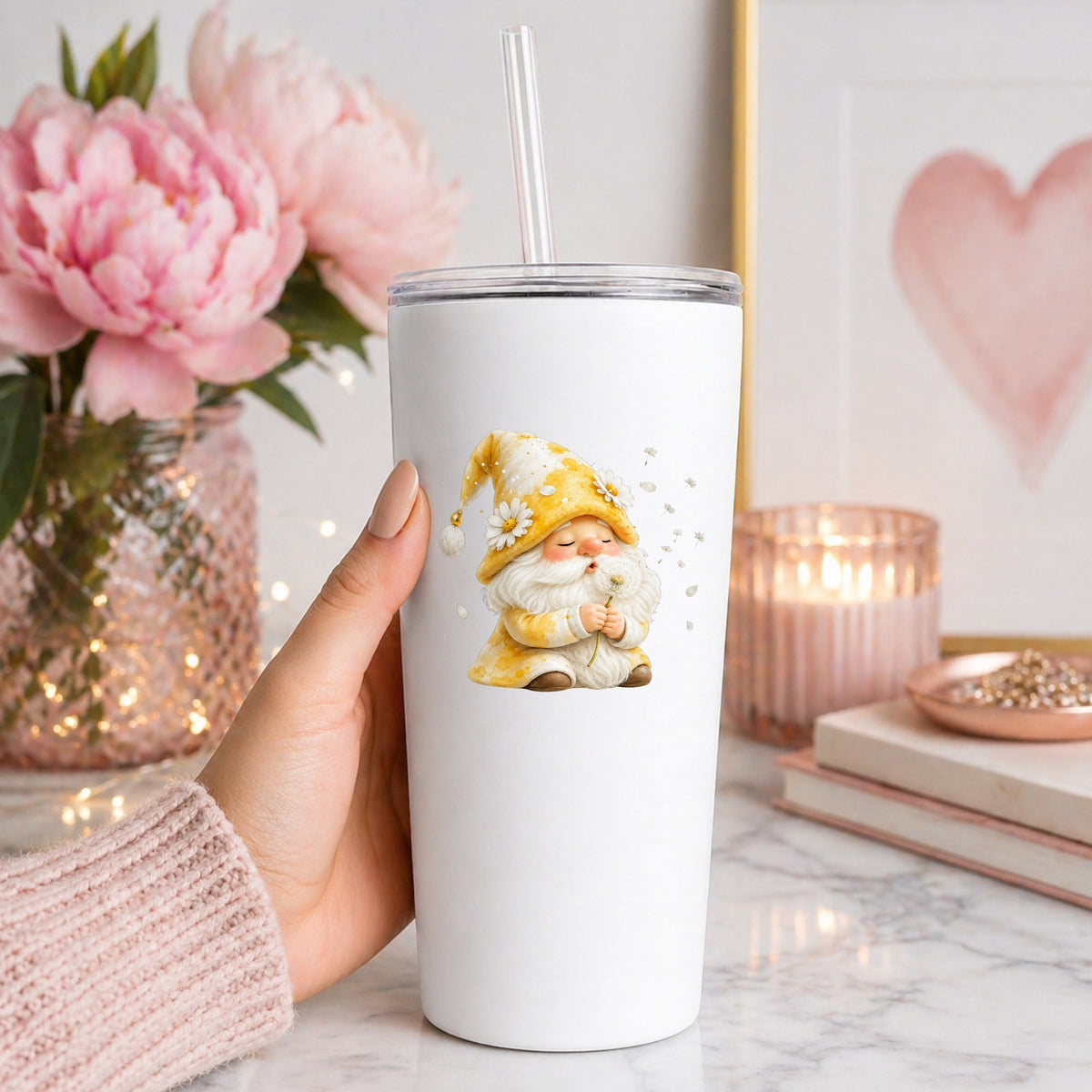 Gnome Blowing A Dandelion UV DTF sticker applied to a white straw tumbler beside pink peonies