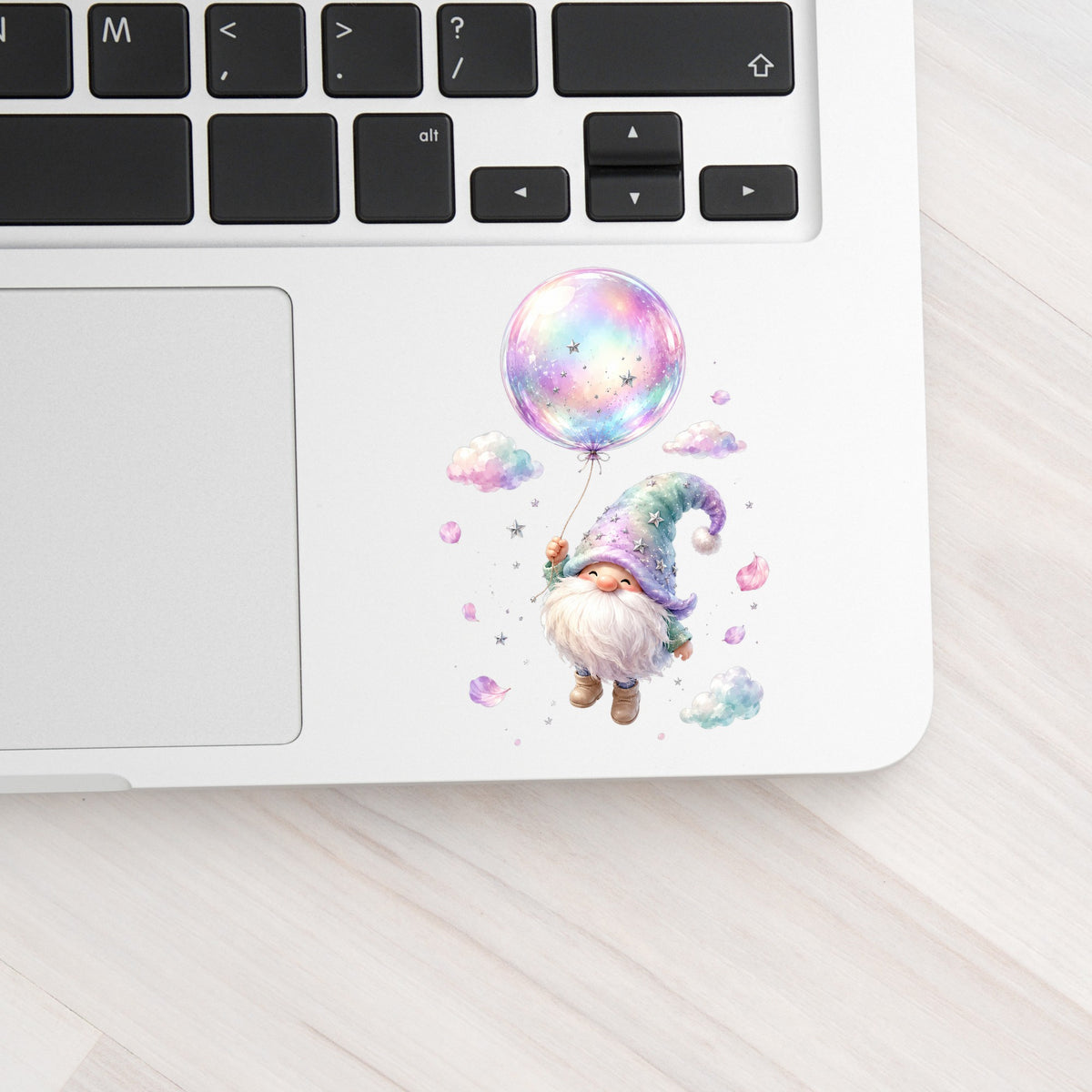 Gnome With Rainbow Bubble Balloon UV DTF sticker applied to a silver laptop beside the keyboard