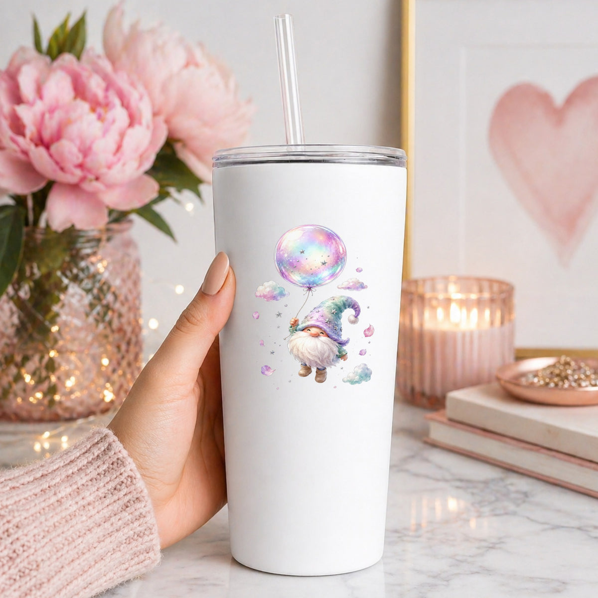 Gnome With Rainbow Bubble Balloon UV DTF sticker applied to a white straw tumbler beside pink peonies