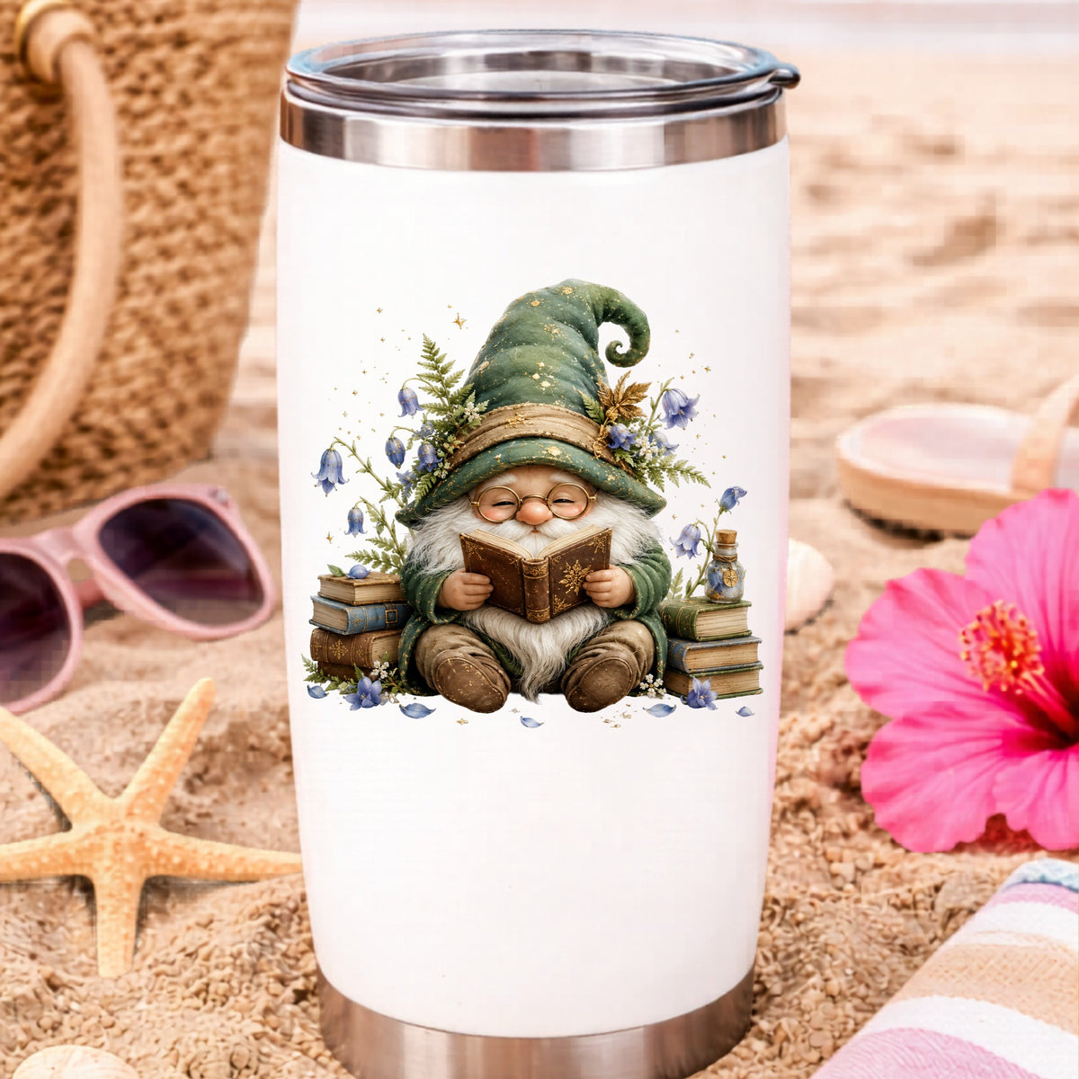Gnome Reading With Book Stack UV DTF sticker applied to a white travel tumbler on beach sand