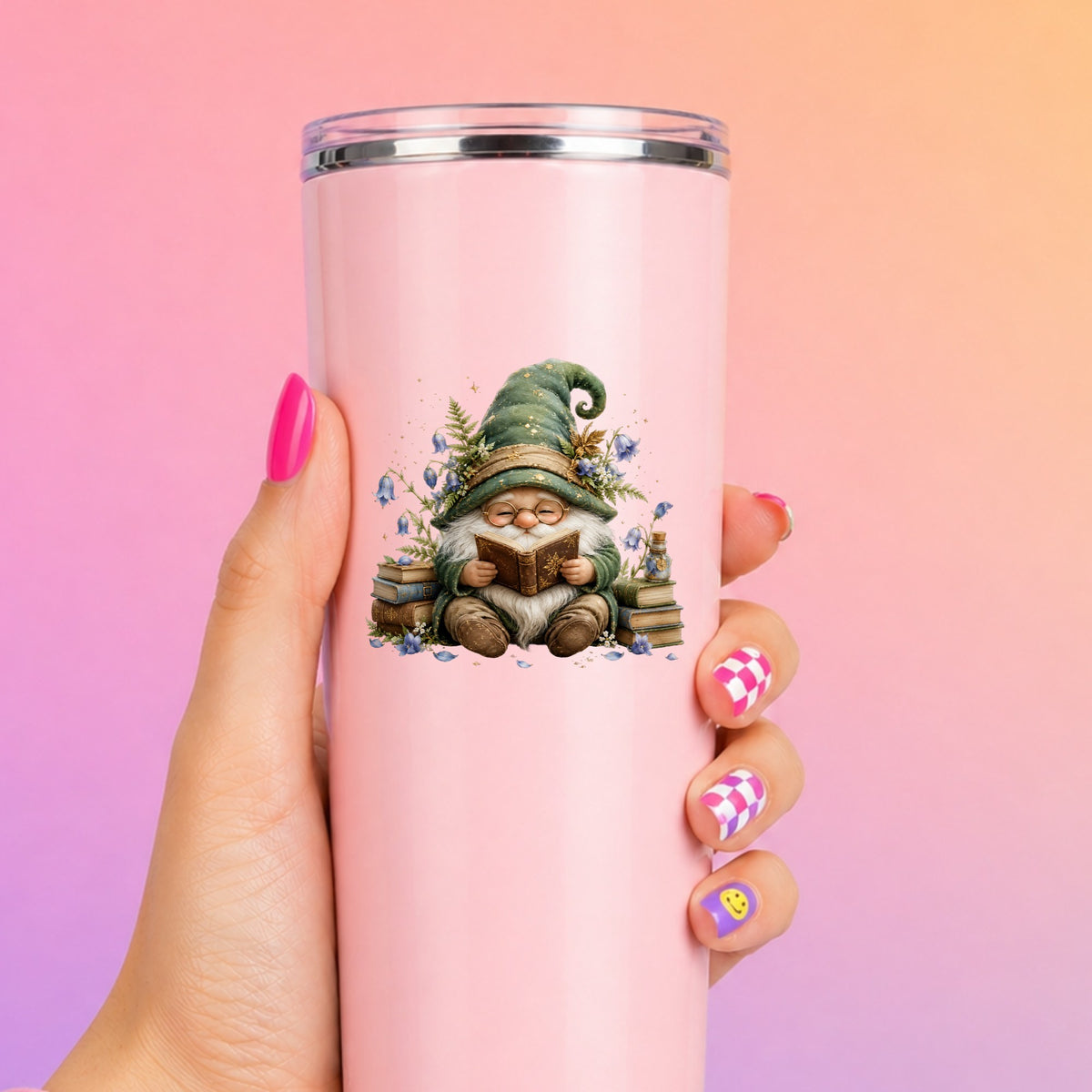 Gnome Reading With Book Stack UV DTF sticker applied to a tall pink tumbler on a pink and orange background